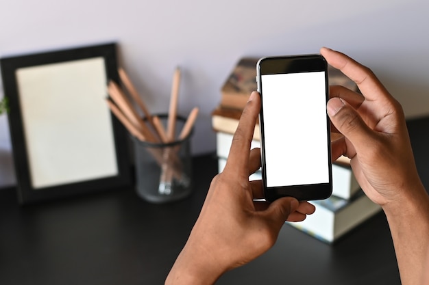 Recadré coup de smartphone sur les mains avec un écran vide sur le bureau.