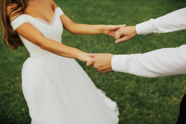 Recadrée en gros plan photo de la mariée et le marié tenant les mains debout sur la cérémonie de mariage