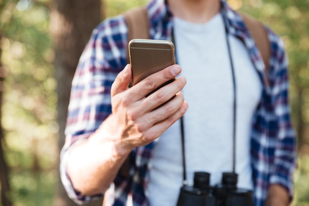 Recadrée d'homme avec téléphone en forêt