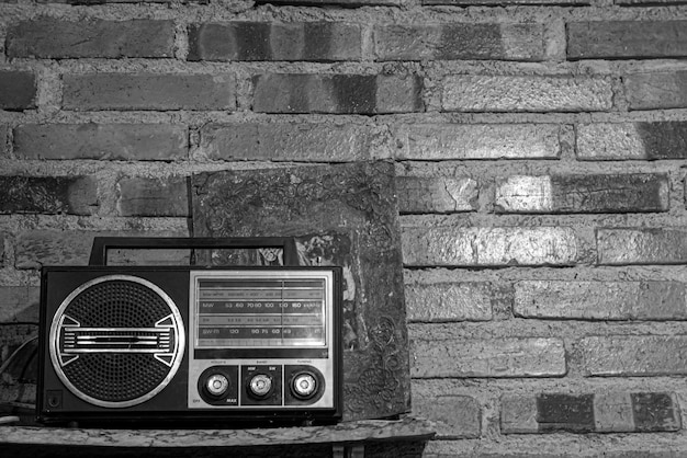 Un récepteur radio rétro vintage blanc noir devant un mur de briques