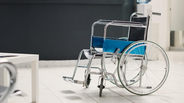 Réception de la clinique médicale avec fauteuil roulant dans le hall d'inscription de l'hôpital, réception vide avec formulaires de rendez-vous. Centre de santé adapté aux personnes handicapées avec brochures médicales. Prise de vue à main levée.