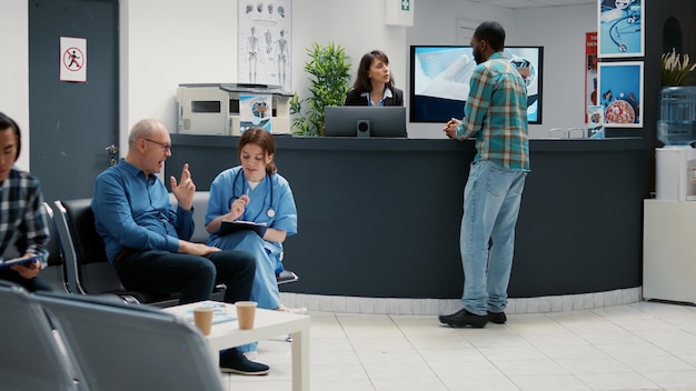 Réception avec divers patients attendant dans le hall pour une visite de contrôle, des personnes écrivant un rapport au comptoir et une mère avec un enfant dans la zone d'attente. Rendez-vous avec le médecin et le personnel médical.