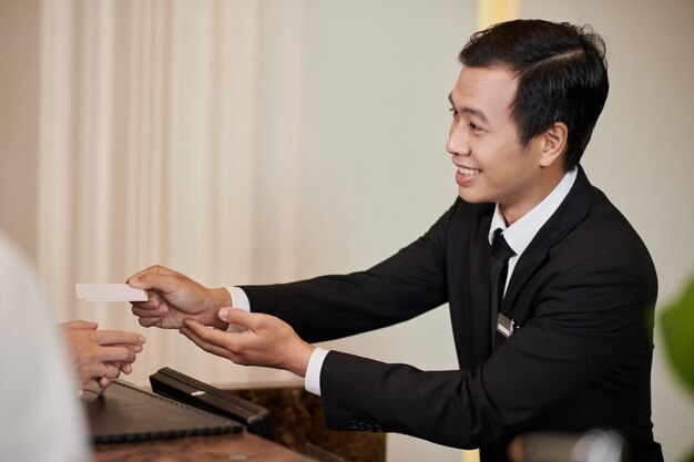 Une réceptionniste d'hôtel souriante donne des clés électroniques aux invités.