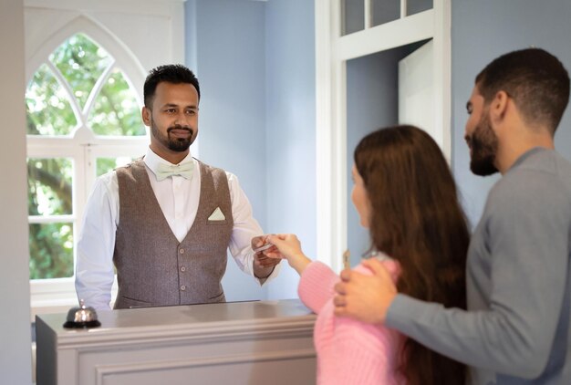 Photo réceptionniste prenant la carte de crédit du couple recevant le paiement pour l'hébergement