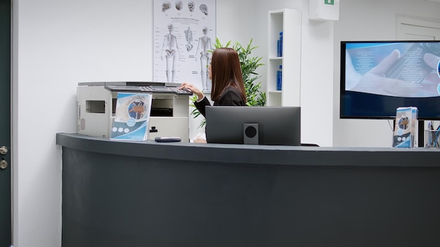 Photo réceptionniste travaillant à la réception de l'hôpital dans un centre médical, aidant à traiter les patients et à prendre des rendez-vous de consultation. répondre au téléphone fixe pour discuter de la visite de contrôle.