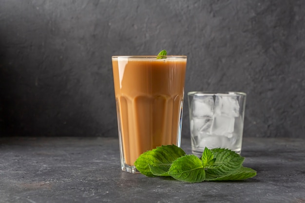 Recette Café glacé à la menthe et au lait. Grand verre de cocktail de café et verre avec des glaçons. Boisson d'été fraîche sur fond sombre dans la clé de la loi. copier l'espace pour le texte