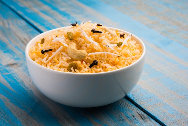 Recette de riz sucré à la noix de coco également connue sous le nom de narali bhat à base de safran, de noix de cajou, de clou de girofle et servie dans un bol blanc. Nourriture konkani ou maharashtrian populaire.