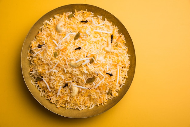 Recette de riz sucré à la noix de coco également connue sous le nom de narali bhat à base de safran, de noix de cajou, de clou de girofle et servie dans un bol blanc. Nourriture konkani ou maharashtrian populaire.