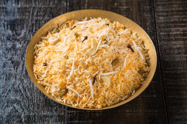 Recette de riz sucré à la noix de coco également connue sous le nom de narali bhat à base de safran, de noix de cajou, de clou de girofle et servie dans un bol blanc. Nourriture konkani ou maharashtrian populaire.