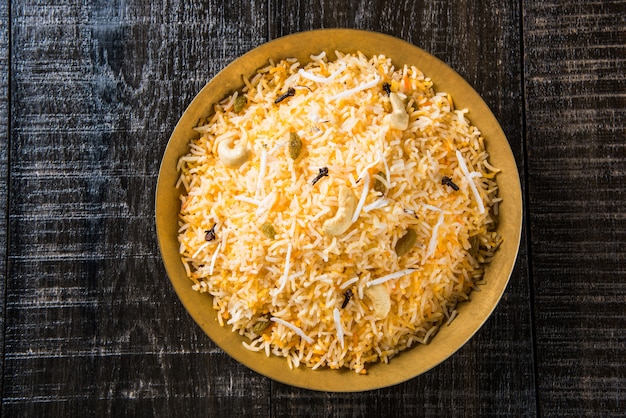 Recette de riz sucré à la noix de coco également connue sous le nom de narali bhat à base de safran, de noix de cajou, de clou de girofle et servie dans un bol blanc. Nourriture konkani ou maharashtrian populaire.