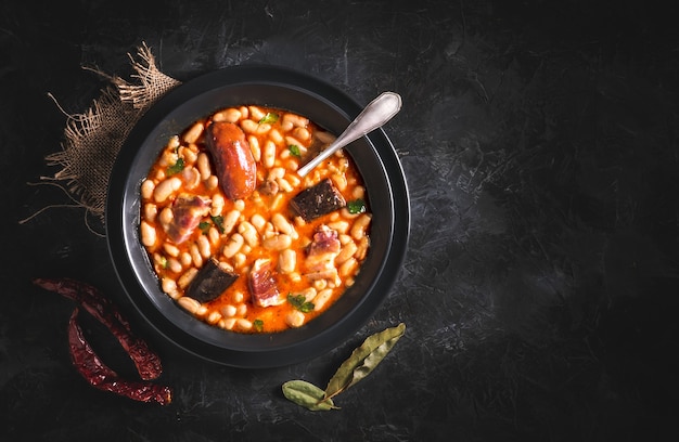 Recette traditionnelle de haricots au chorizo et boudin appelé Fabada Asturiana sur une table sombre