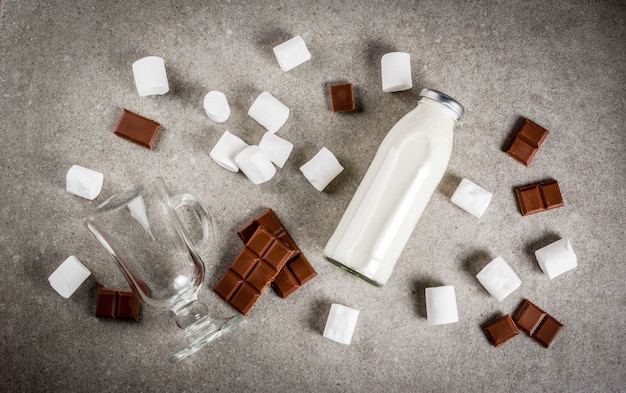 Photo recettes de boissons chaudes de noël, ensemble d'ingrédients pour le chocolat chaud: bouteille de lait, chocolat, guimauve, copie espace vue de dessus