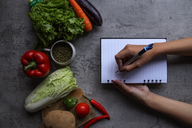 recettes d'écriture à la main sur un livre avec des ingrédients alimentaires et des légumes frais dans la cuisine