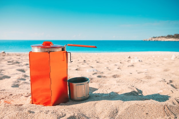 Photo réchaud de camping avec pare-vent cuisson des aliments de randonnée sur une plage de sable