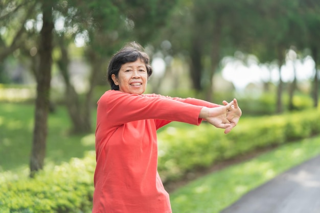 Réchauffement du corps d'une femme asiatique âgée avant de faire de l'exercice Vieille femme s'étirant avant de faire du jogging dans le jardin