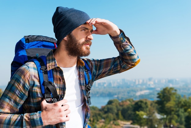 A la recherche de nouveaux horizons. Beau jeune homme portant un sac à dos et regardant loin