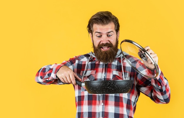 À la recherche d'un restaurant parfait Récipients de cuisson en fonte émaillée Poêle antiadhésive recouverte de téflon Cuisson d'aliments sains Chef professionnel homme cuisinier en chemise à carreaux mari barbu