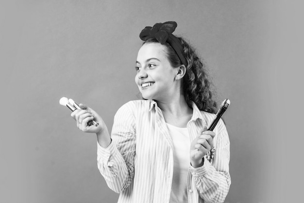 À la recherche de soins parfaits pour les cheveux et la peau petite fille porter bandeau vintage enfant cosmétiques et maquillage enfance heureuse mode beauté coiffeur salon de beauté fille rétro mettre le maquillage naturel avec une brosse