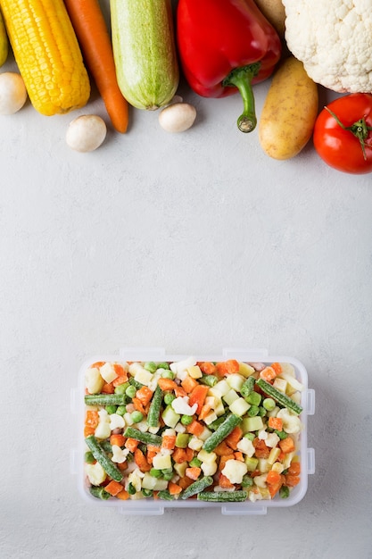 Récipient en plastique rectangulaire avec mélange de légumes surgelés vue de dessus avec place pour le texte et les aliments frais