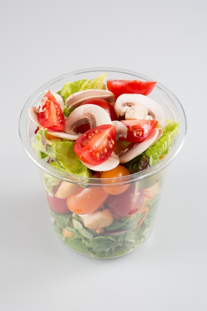 Récipient en plastique de salade à emporter salades sur blanc