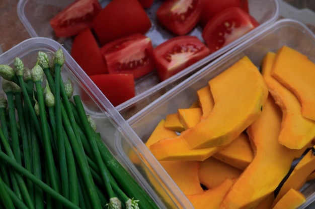 Un récipient en plastique avec des tomates et des haricots verts.