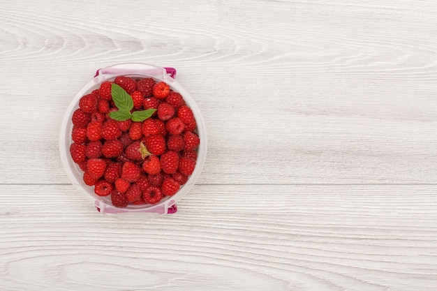 Récipient de préparation de repas en plastique avec des framboises fraîches sur fond gris avec espace de copie