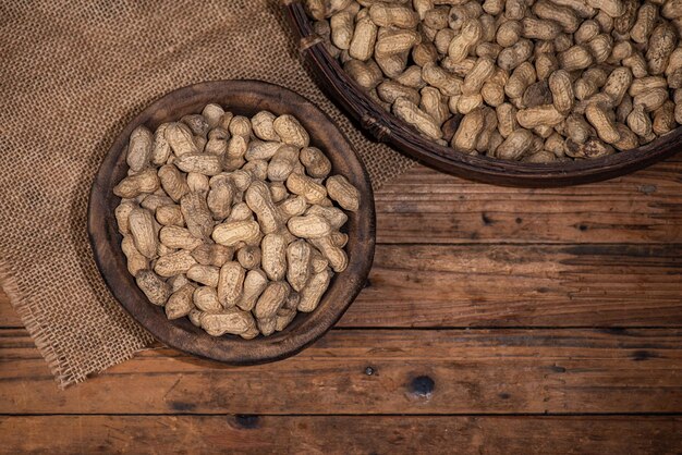 Le récipient sur la table de grain de bois est plein d'arachides