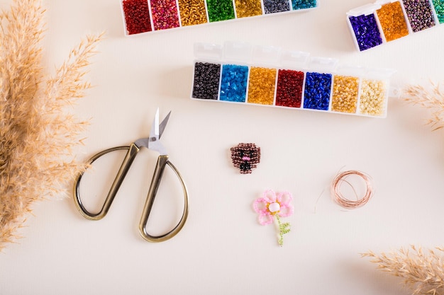 Récipients avec fil de perles colorées et ciseaux pour fabriquer des jouets à partir de perles Couture et fait à la main