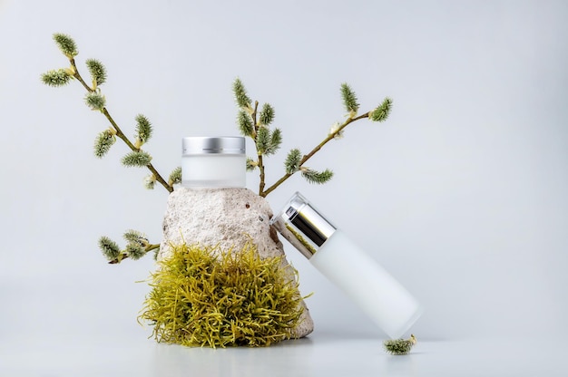 Récipients pour cosmétiques naturels sur le podium en mousse de pierres et branches de saule