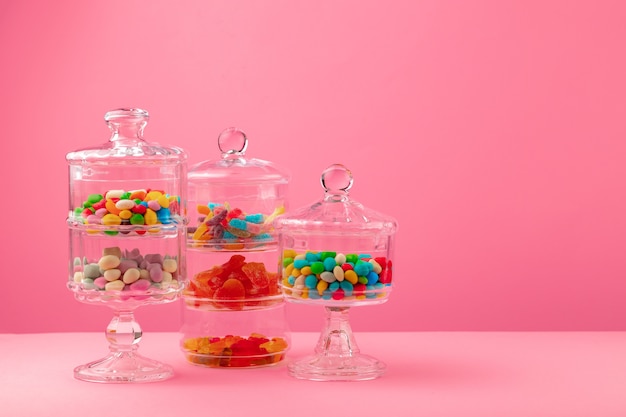 Récipients en verre avec des bonbons et des bonbons contre le rose