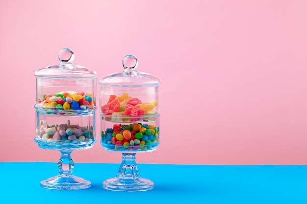 Récipients en verre avec des bonbons et des bonbons contre le rose