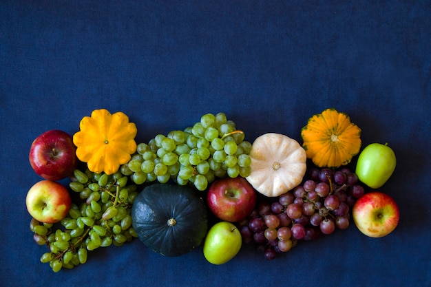 Récolte d'automne et d'automne, citrouille, pomme, raisin et pattison sur la table bleue