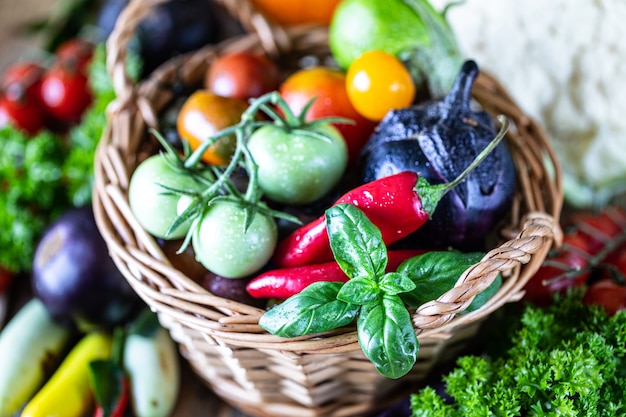 Récolte d'automne de légumes dans un panier en osier: tomates, haricots, courges, citrouille, chou, légumes verts, persil.