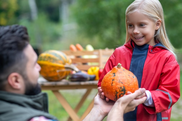 Récolter la récolte. Papa et sa fille trient les citrouilles dans la cour