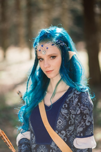 Reconstitution historique. Jeune femme archer aux cheveux bleus dans une robe historique avec arc.