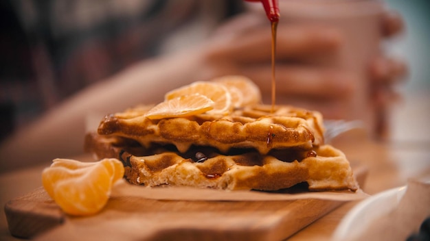 Recouvrement d'une gaufre belge entourée de tranches de mandarines avec un sirop café cuisine