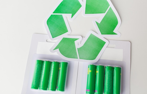 Recyclage des déchets, élimination des ordures, environnement et concept d'écologie - gros plan de piles alcalines usagées et symbole de recyclage vert