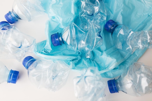 recyclage des déchets, réutilisation, élimination des déchets, concept d'environnement et d'écologie - gros plan de bouteilles d'eau en plastique usagées vides et d'un sac poubelle sur la table