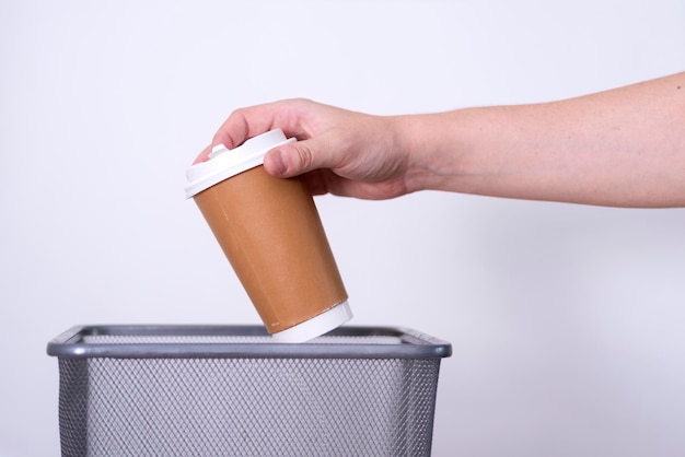 Recyclagela main de collecte des déchets séparée jette une tasse de café dans la poubelle