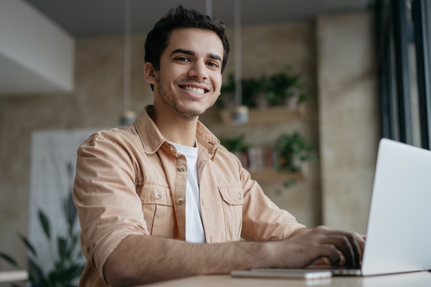 Rédacteur pigiste souriant à l'aide d'un ordinateur portable, travail à domicile