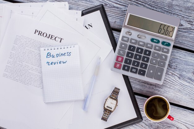 Rédaction de revue d'entreprise. Projet d'entreprise avec calculatrice et tasse de café sur table en bois. Flay vue de dessus.