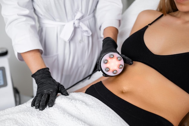 La réduction de la graisse du ventre est au centre de l'attention alors qu'une jeune femme subit un lifting de cavitation du corps à la beauté