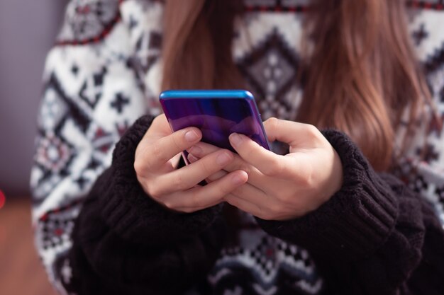 Réductions de Noël. La fille choisit des cadeaux sur un téléphone portable