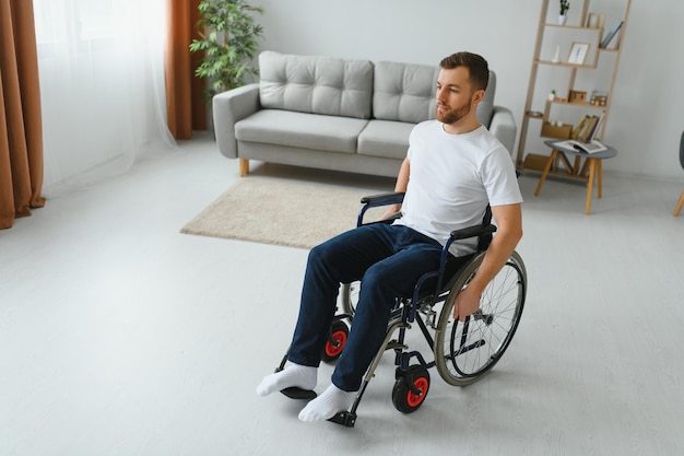 Réfléchi jeune homme handicapé en fauteuil roulant à la maison