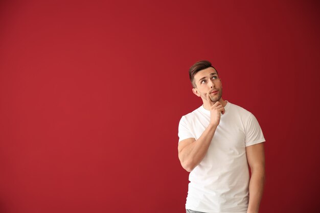 Réfléchi jeune homme sur mur rouge