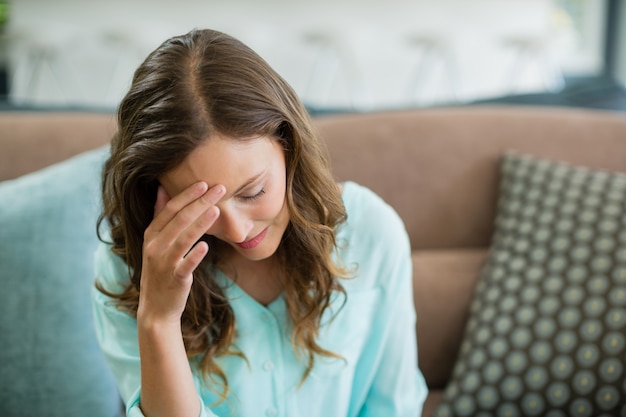 Réfléchie femme assise sur un canapé dans le salon