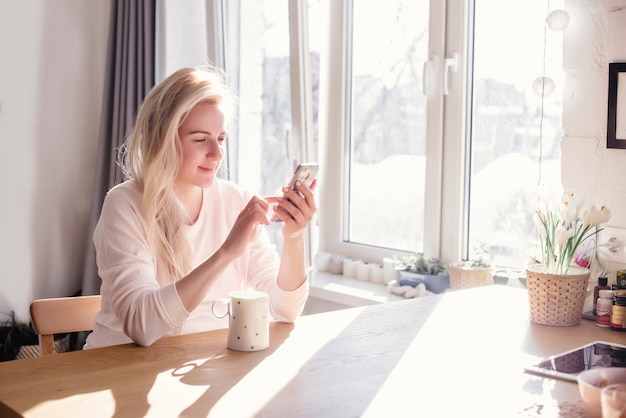 Réfléchie jeune femme en peignoir manger le petit déjeuner dans la cuisine