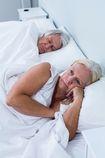 Réfléchie senior femme allongée sur le lit