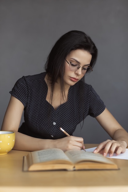 Réfléchir à la jolie jeune femme avec un stylo à la main en pensant et en prenant des notes. Belle jeune