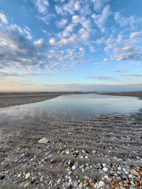 Reflet d'un ciel nuageux dans la mer à l'aube en bord de mer